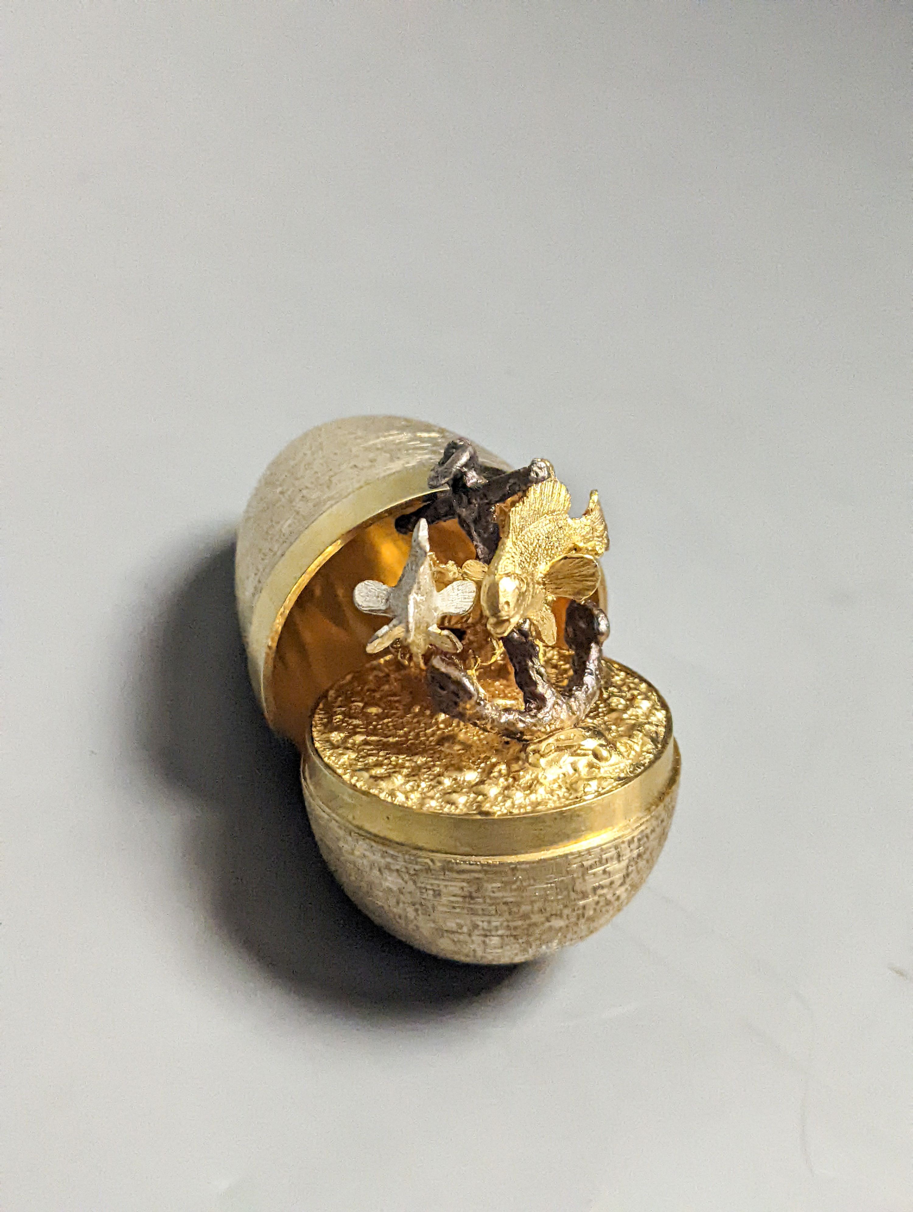 A 1970's textured silver gilt surprise egg by Stuart Devlin, opening to reveal a ship's anchor with fish, London, 1977, 71mm, no box or certificate.